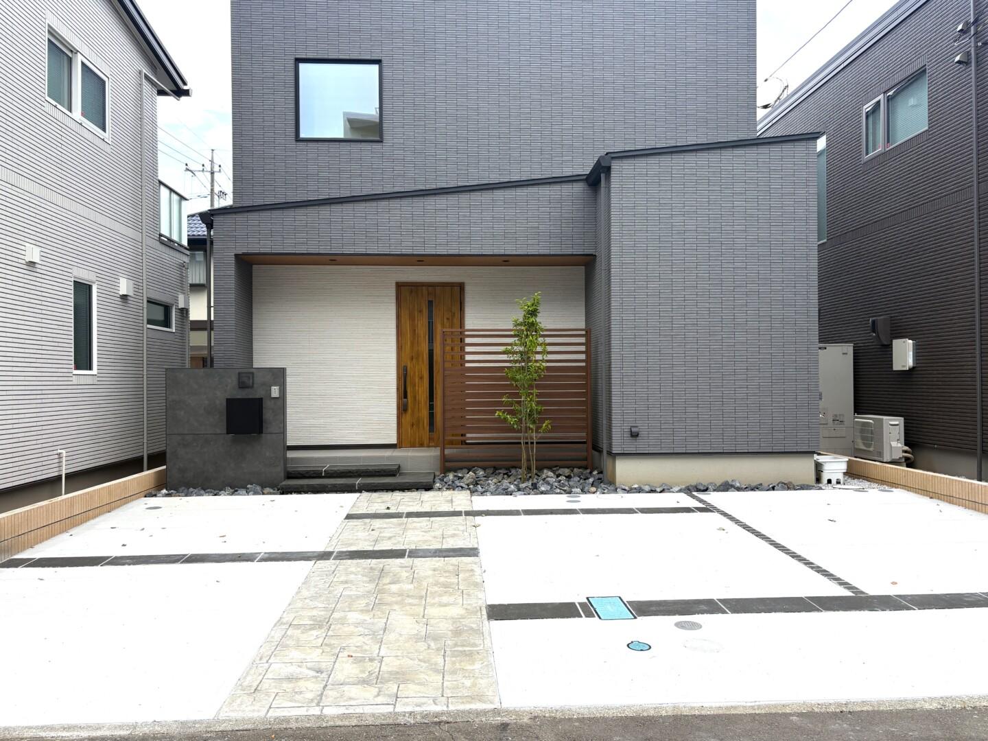 スタンプコンクリートのアプローチと自然石の浮き階段が調和したモダンな外構全景