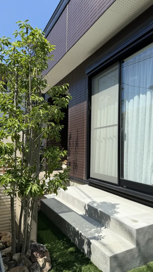 雑草管理を軽減する人工芝とコンクリートテラスで仕上げた庭まわり