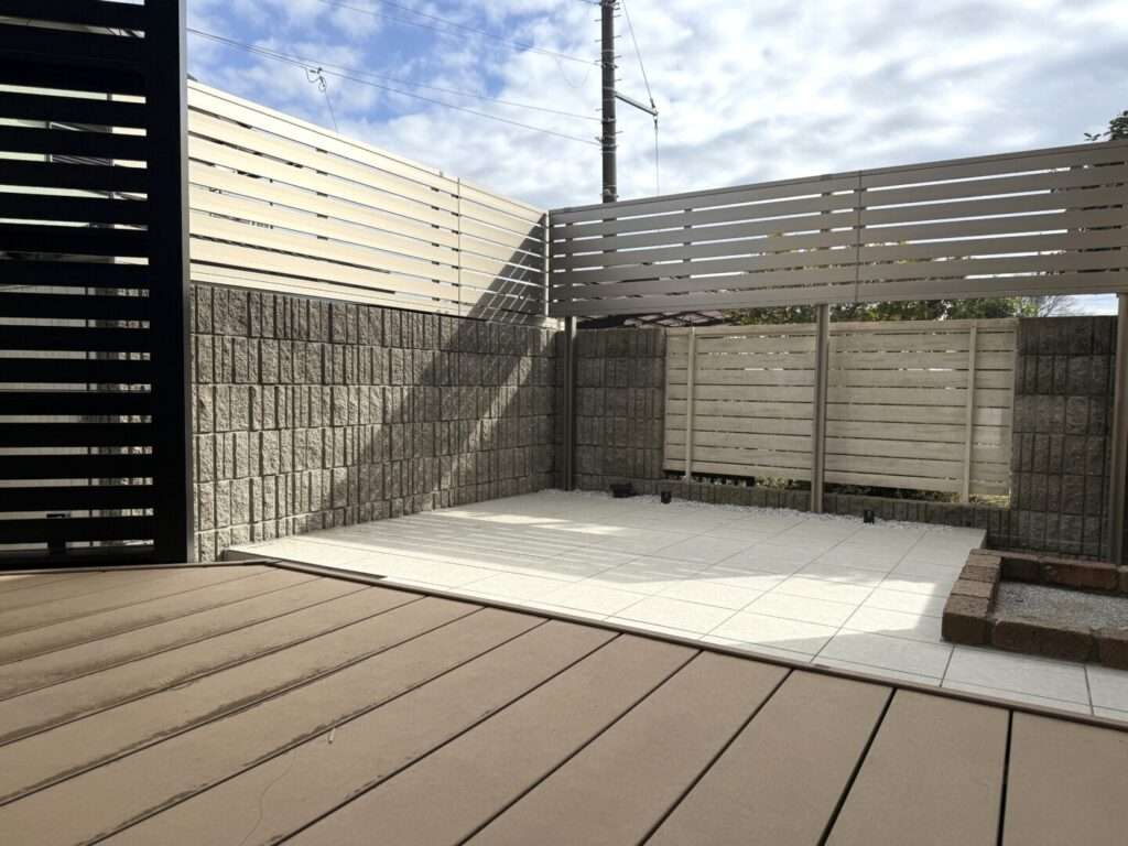 狭山市の施工例:明るいタイルデッキと目隠しフェンスでリノベーションした開放的な庭の全景