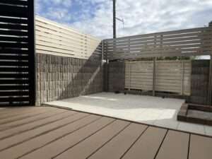 狭山市の施工例：明るいタイルデッキと目隠しフェンスでリノベーションした開放的な庭の全景