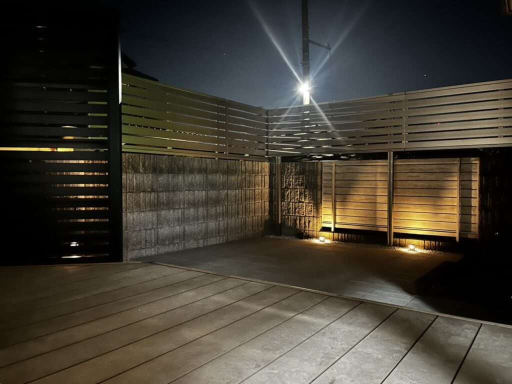 狭山市の施工例:明るいタイルデッキと目隠しフェンスでリノベーションした開放的な庭の夜景