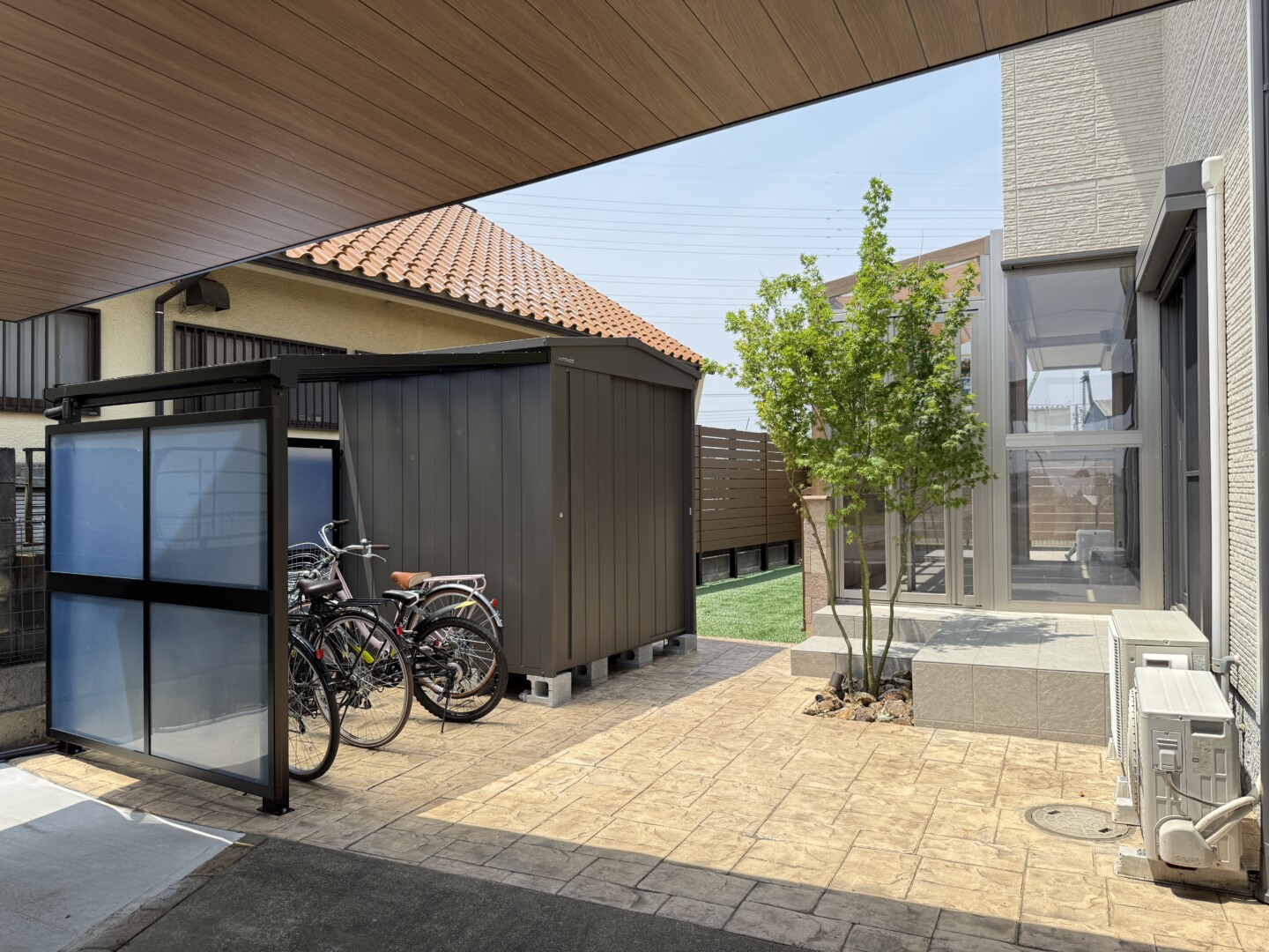 お庭への入り口に設置されたスタンプコンクリートと、駐輪場、三角屋根が特徴のおしゃれなマツモト物置