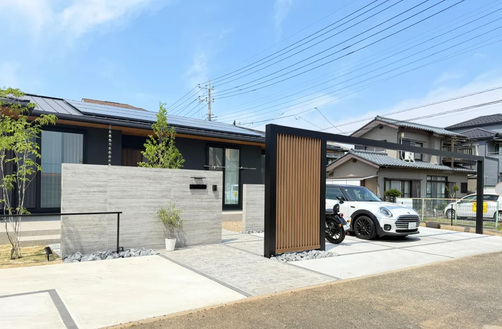 川越市の新築外構・タカショーセラシリーズの木目調大判タイルを横張りした存在感ある門塀。平屋の水平ラインと呼応した落ち着いた高級感のあるファサード。