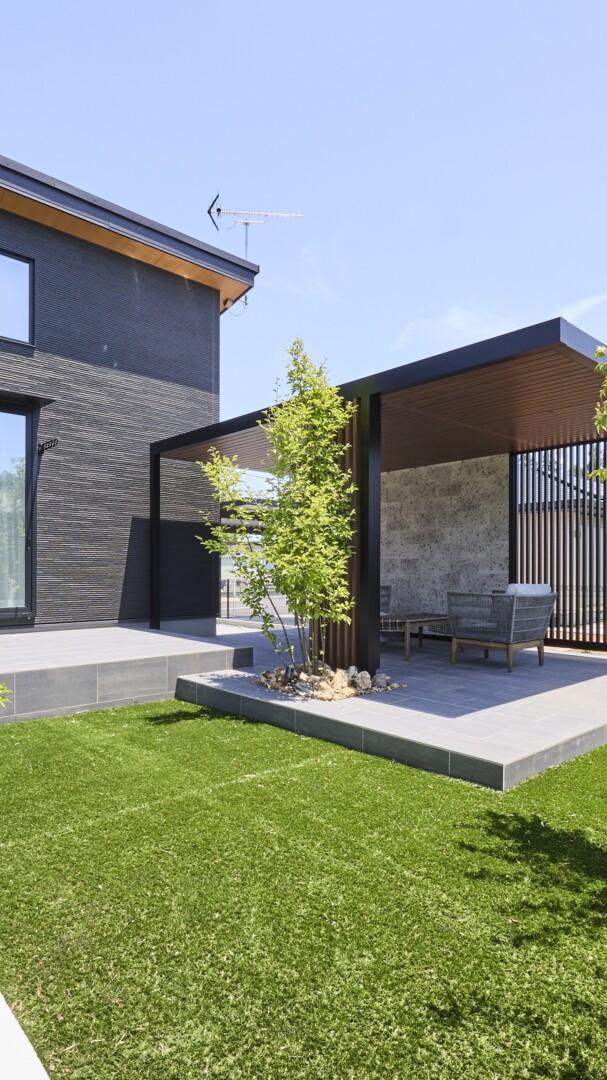 大判タイルで施工した階段状のタイルデッキ。人工芝と調和した快適空間