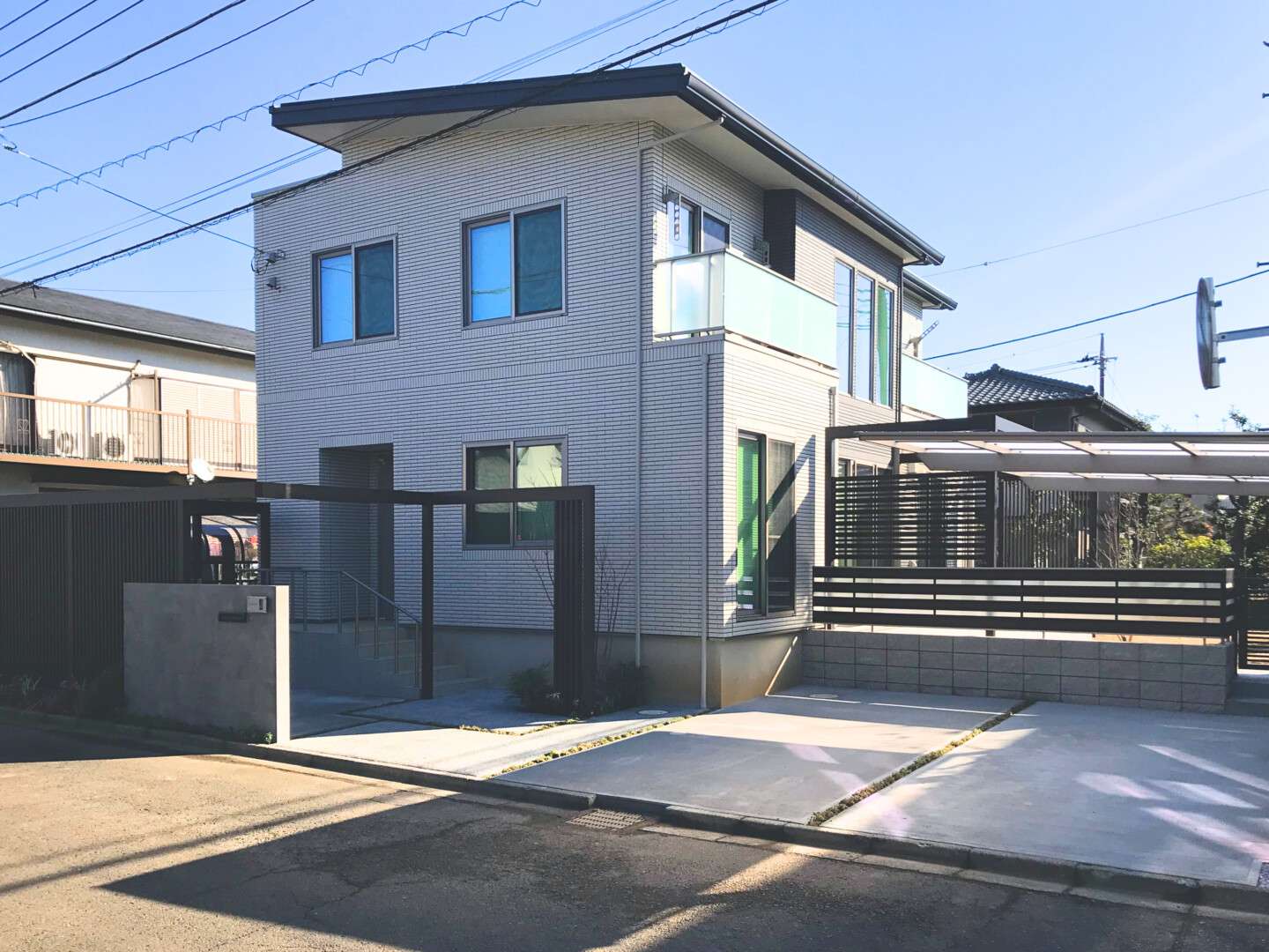 一条工務店の建物に調和する、LIXILプラスGのL字フレームと大判タイル門柱を組み合わせた庭まわりも含め統一感のある新築外構全景