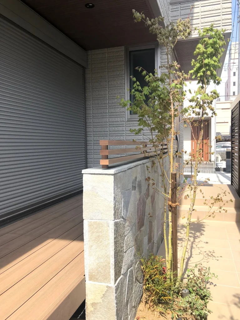 乱形自然石貼りの塀と建物外壁との取り合い部分。異なる素材の組み合わせが上質な雰囲気を生む。