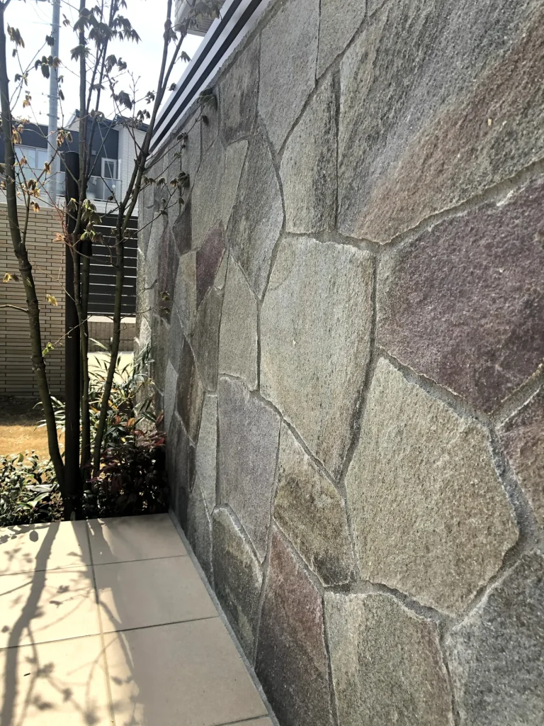 L字型の建物形状に合わせて作った塀と乱形自然石貼りのクローズアップ。外構全体のアクセントとなる素材感。