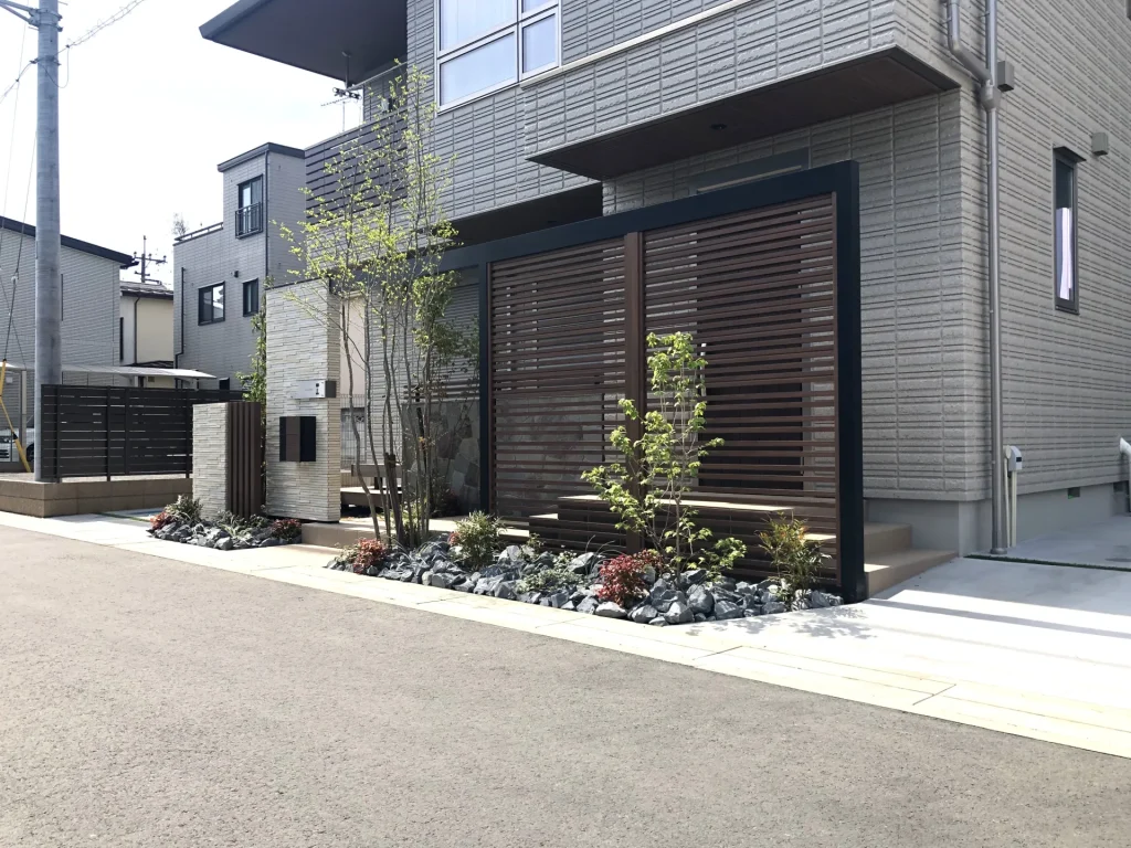 玄関前に設置した横格子のGスクリーン。ブラックフレームと木調色の組み合わせがモダンな印象を与える目隠しフェンス。