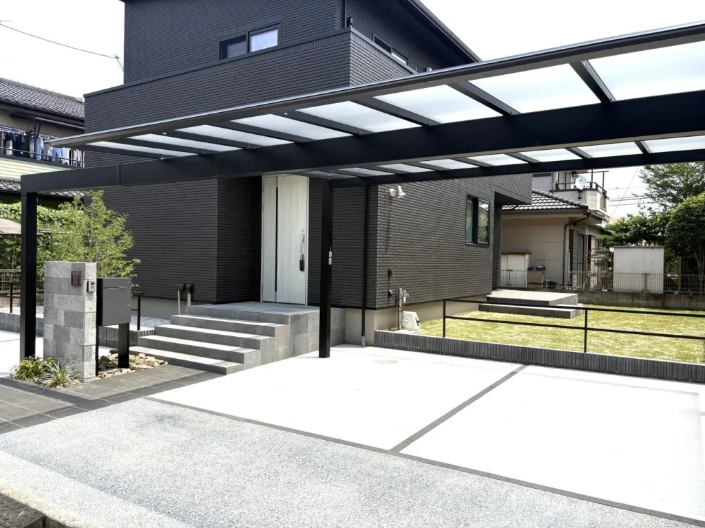 重厚な建物に対してあえて軽やかなポリカ屋根のカーポートを選びバランスをとった外構